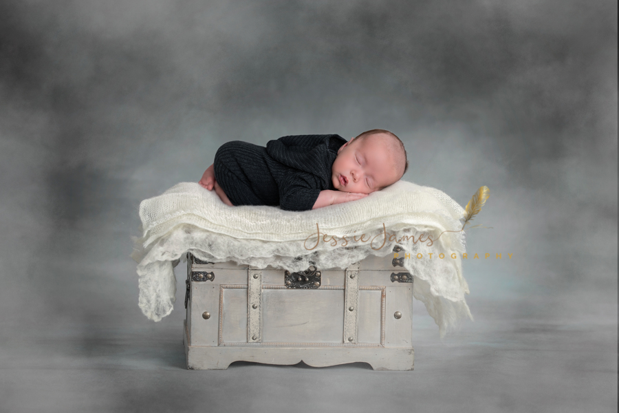baby boy sleeping on a treasure chest with a gray background