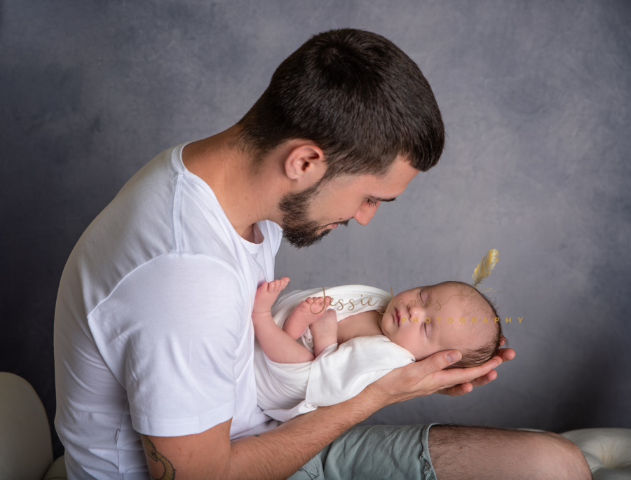 father posing with his newborn baby boy, father holding his newborn baby boy, dad holding baby with head in his hands and feet up against his chest, father and son newborn photo