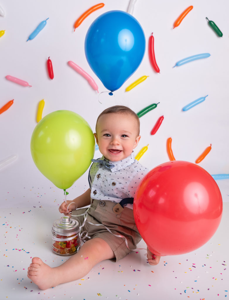 baby boy holding balloons