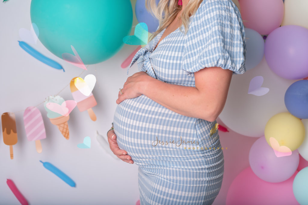 maternity bump standing in front of an ice cream themed backdrop
