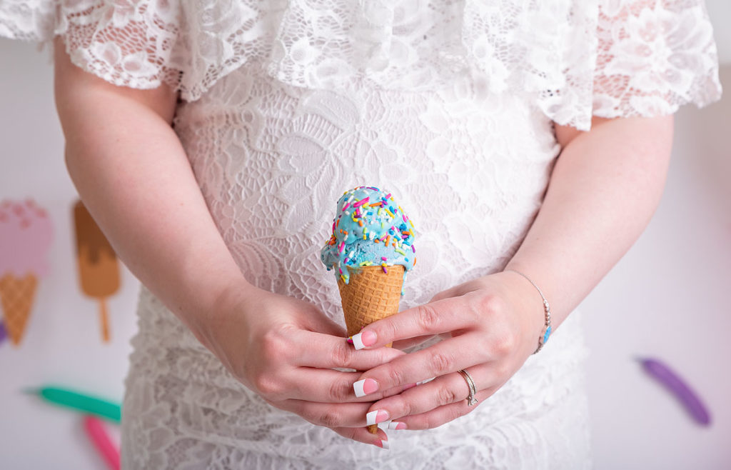 maternity photoshoot, pregnant woman holding a blue ice cream cone wearing a white maternity dress