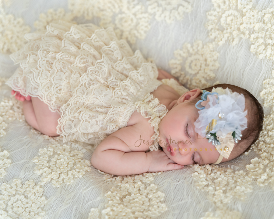 newborn baby girl laying on her belly sleeping on a lace blanket, newborn photography pose, tushie up pose