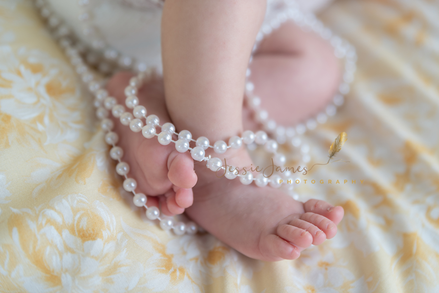 newborn baby girl feet wrapped in pearls