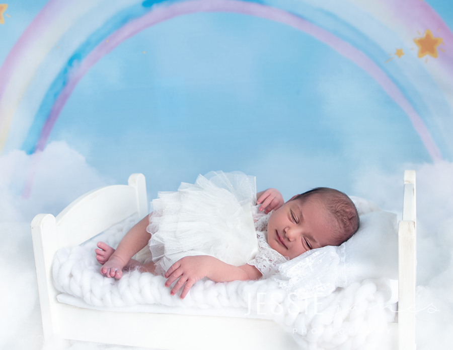 baby smiling on a bed with a rainbow backdrop, baby loss awareness