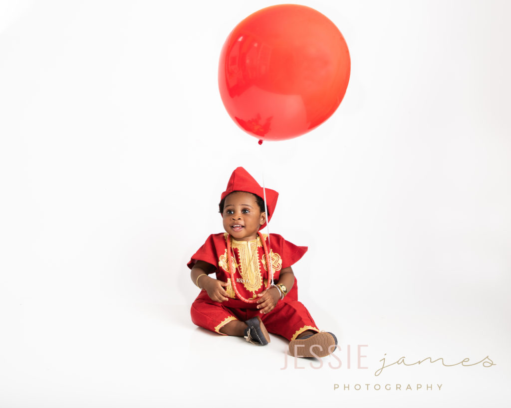 baby boy holding a giant red balloon for his first birthday portraits