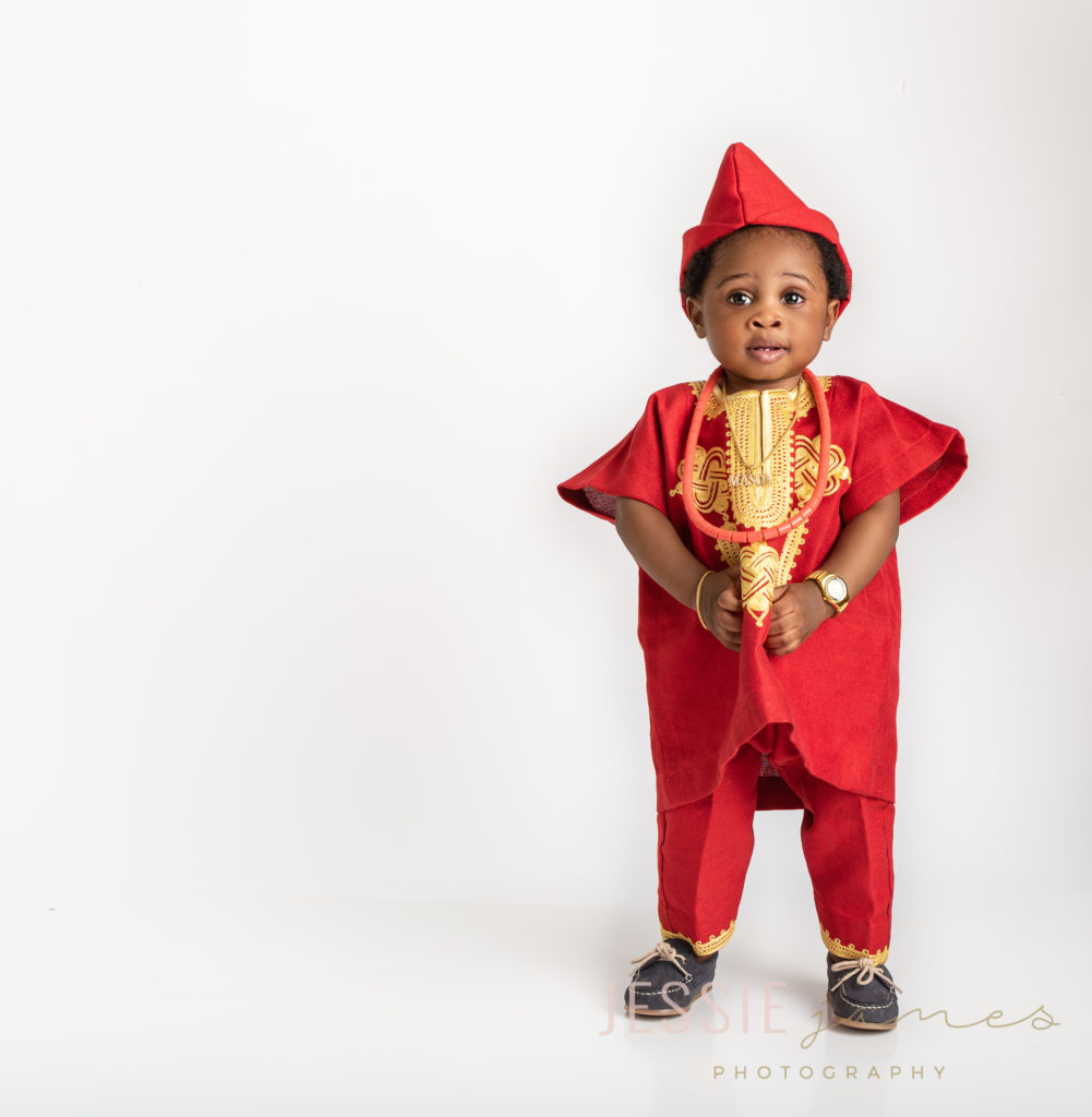 baby boy first birthday portraits wearing a red African outfit with a white backdrop