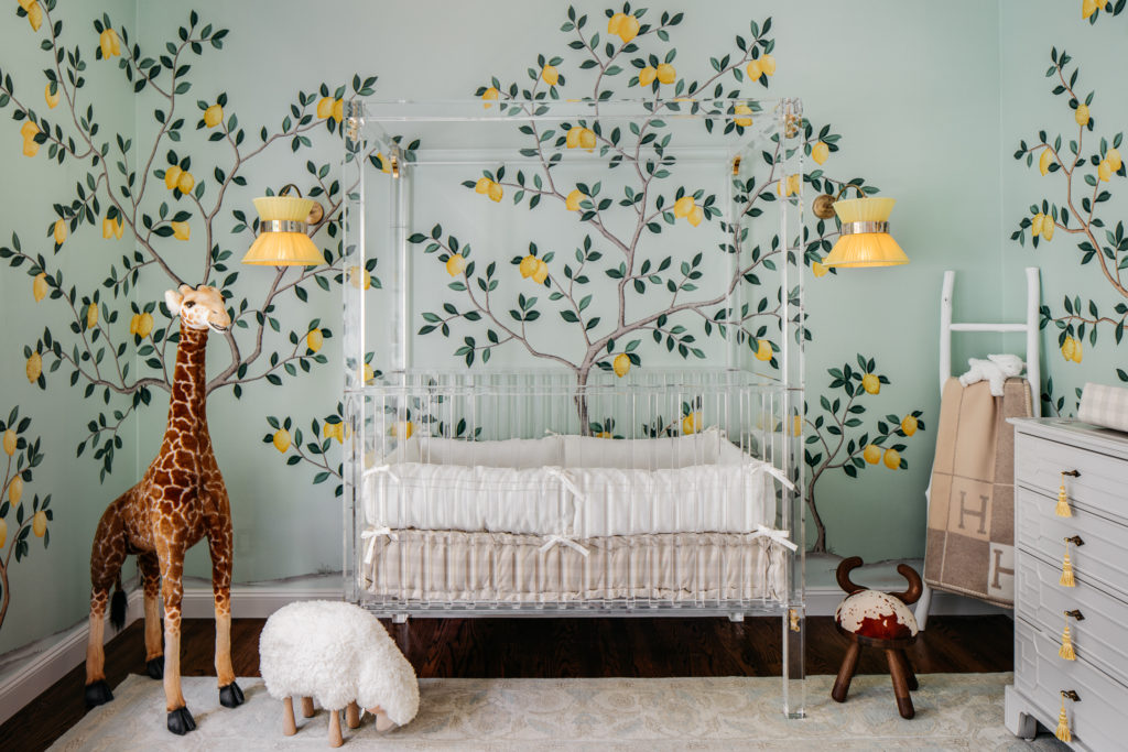 lemon nursery theme, nursery trend for 2020, nursery with lemon tree mural on the wall, with a clear acrylic crib and cute jungle animal stuffed animals