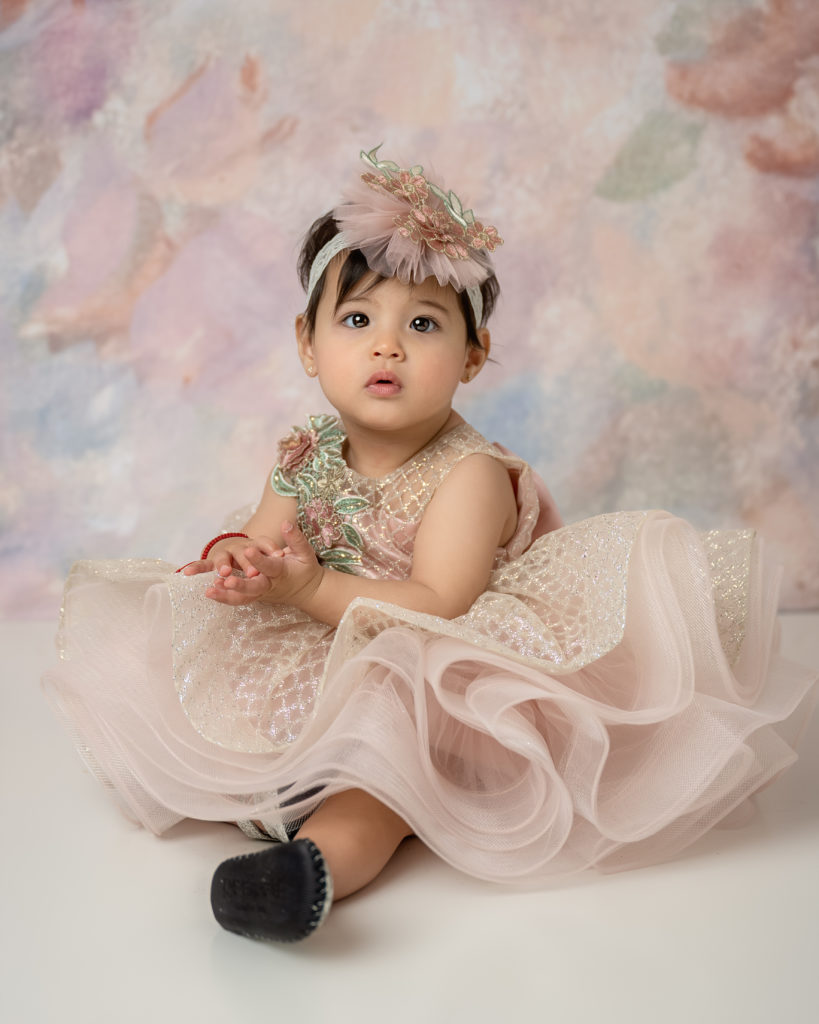 portrait of a baby girl in a pink and gold dress. 