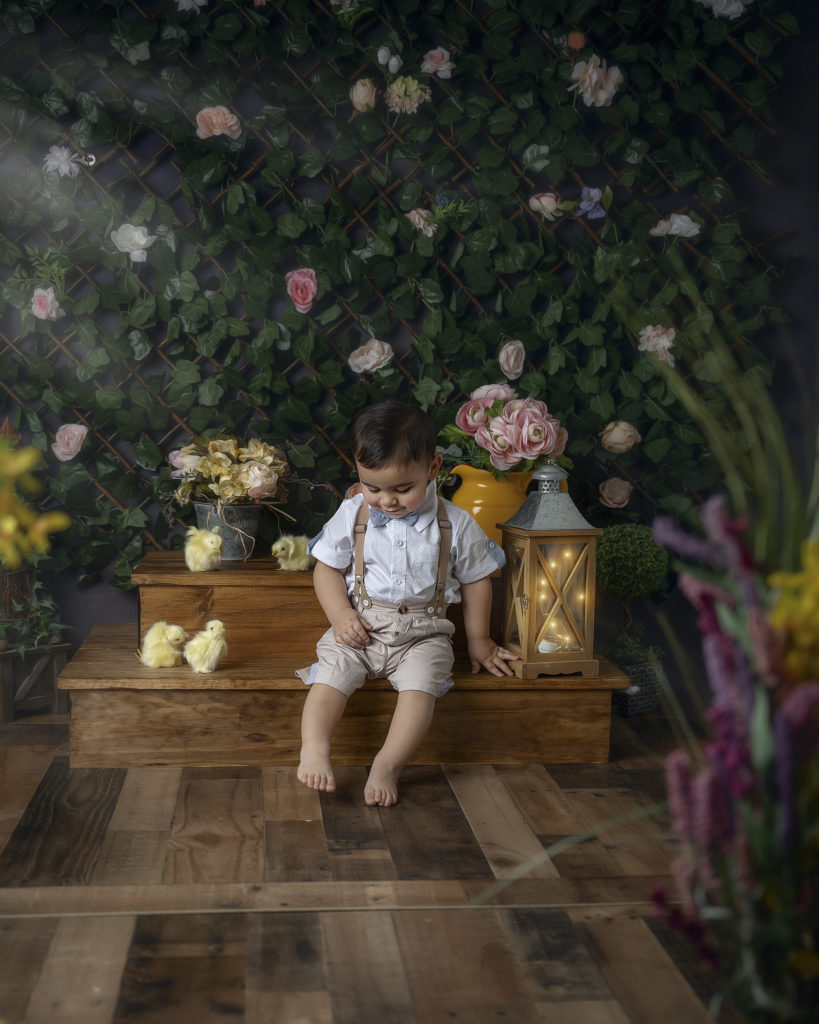 Little boy sitting on steps with chicks, looking at his toes.