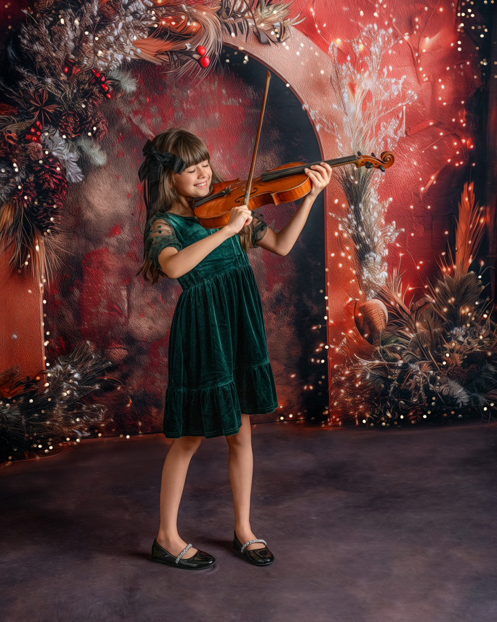 A little girl playing the violin in the Twilight Holiday Lights set, surrounded by twinkling lights and festive greenery.