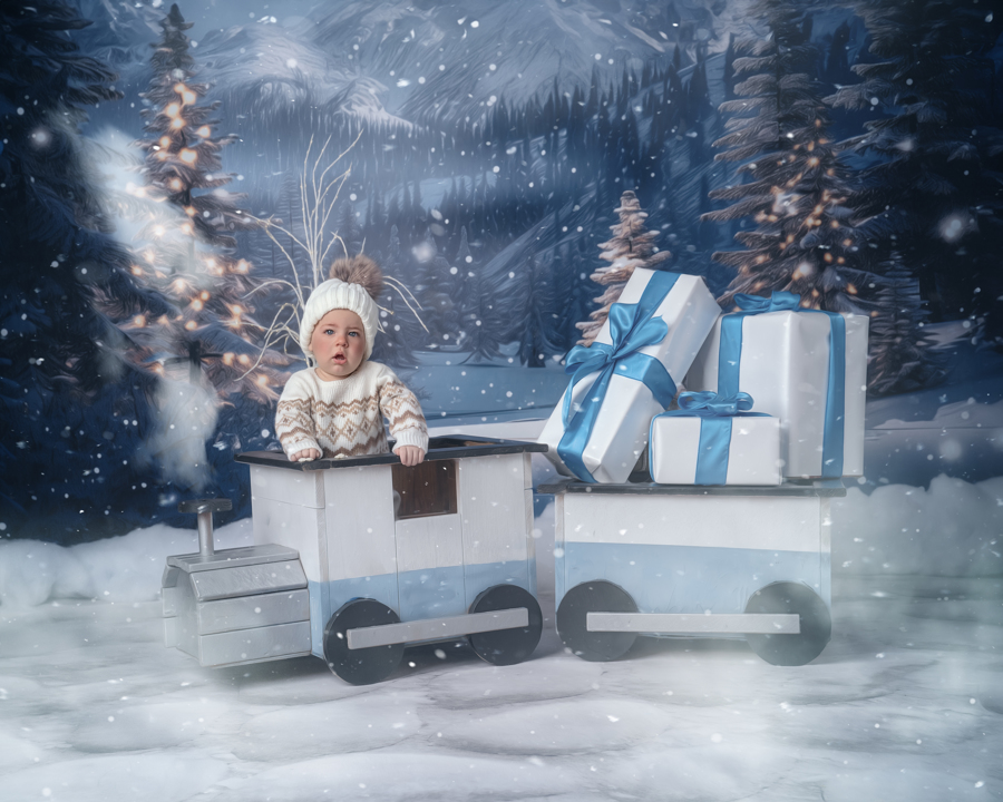 A baby boy sitting in a train in the North Pole Express set, surrounded by snowy decorations and festive lights.