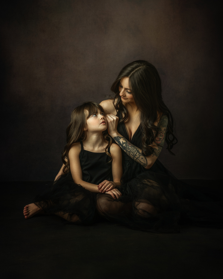 A mother and daughter sit on the floor, gazing into each other’s eyes in a beautifully styled Mommy & Me Mini Session in Staten Island. The cinematic lighting and deep tones give this portrait a timeless, artistic feel.